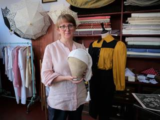 Alison holds a 19th century mannequin head which has been used to display the football cap.