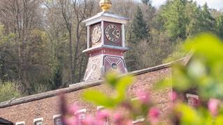 The clock tower of the Coalbrookdale Museum of Iron, fronted by some blurred foliage. The clock displays the time 4:05pm.
