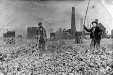 Workers roasting coal to make coke at Blists Hill blast furnaces. The chimneys of the brickworks can be seen in the background. c1900.