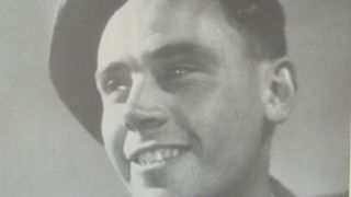A black and white photograph of a young man, smiling, wearing WWII army uniform